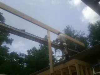 Carpenter setting a ridge beam over a new addition frame — Ice Dam Removal by Roofing Brothers in Angola
