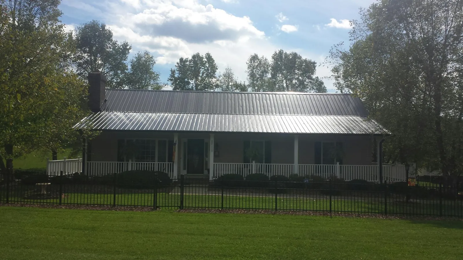 Gray metal roof on a brick ranch with a full width front porch — Gutter Guard Installation work by our crew in Angola