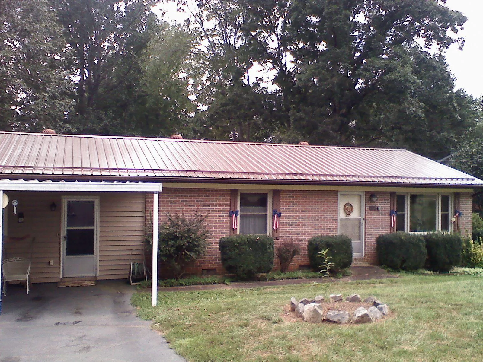 Bronze metal roof and carport on a brick ranch home — Roof Repair work by our crew in Angola
